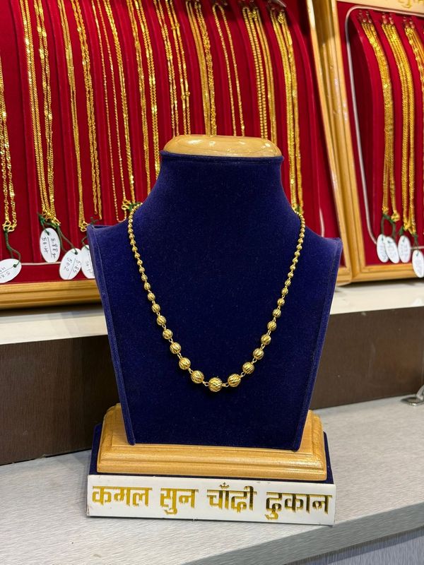 Fine chain with spaced decorative beads on a blue velvet stand