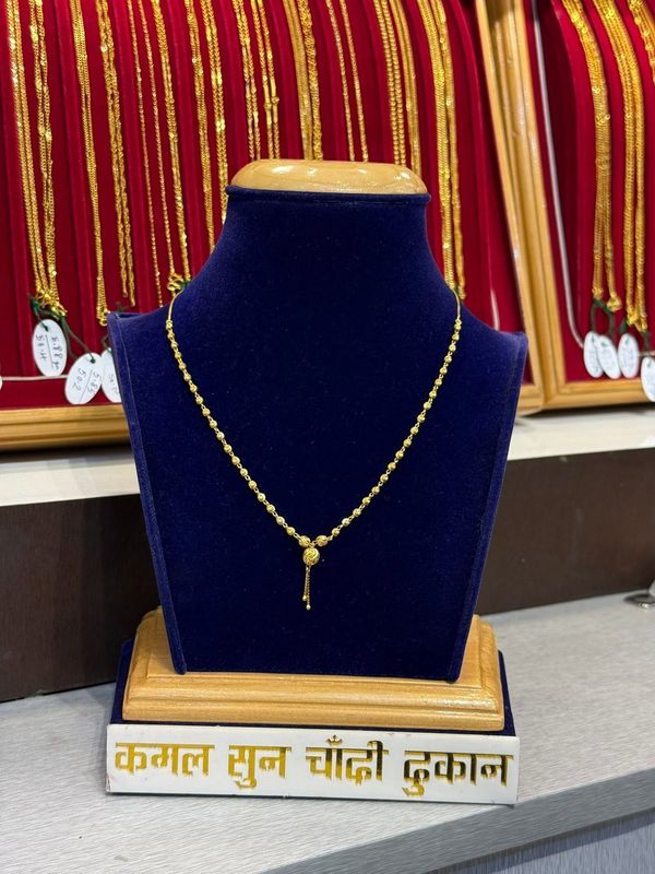 Fine chain with a small drop pendant on a blue velvet stand